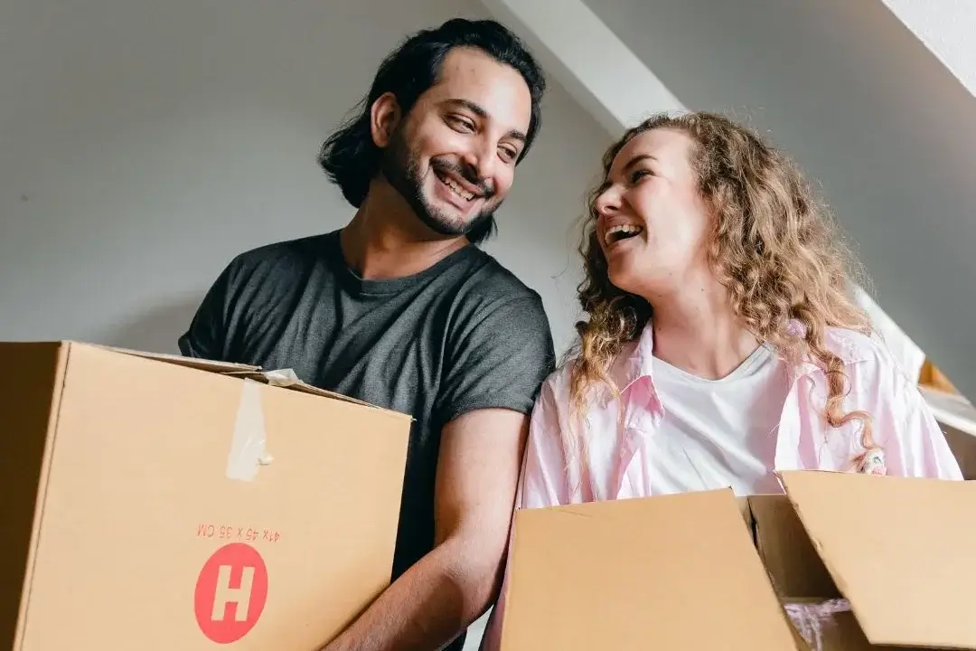 Pareja mudándose de casa con cajas en mano.