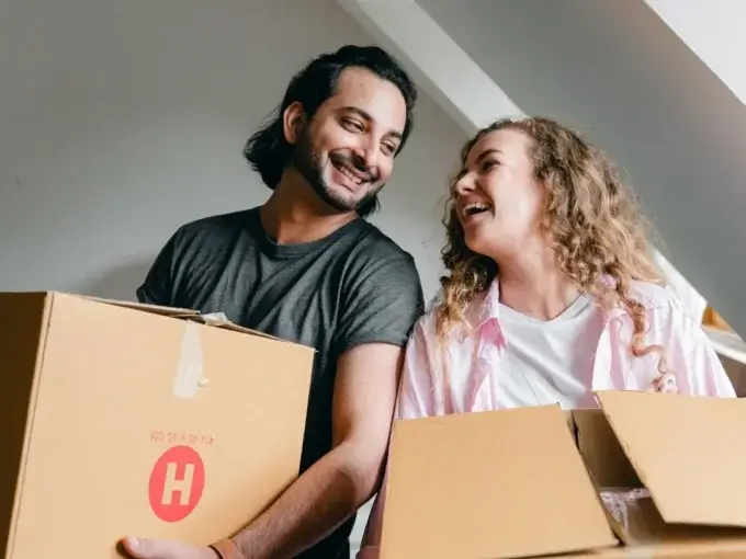 Pareja mudándose de casa con cajas en mano.