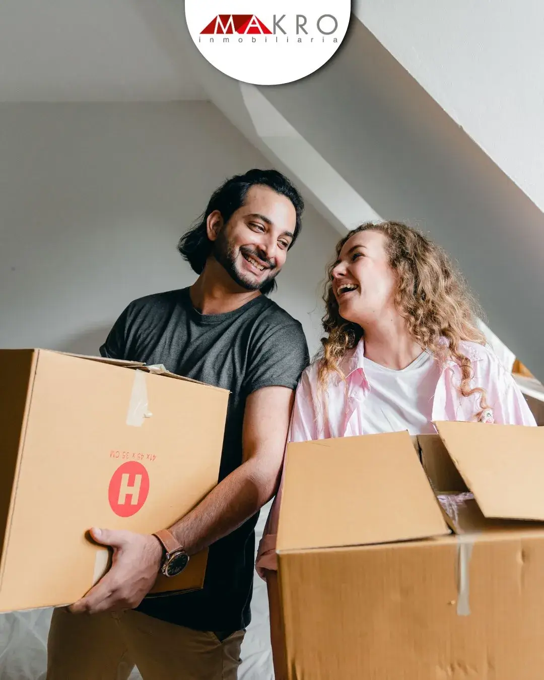 Pareja mudándose de casa con cajas en mano.